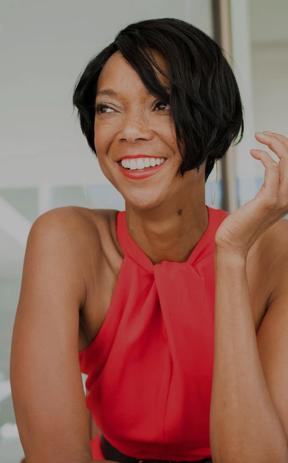 Portrait of Trinette Faint smiling in a sleeveless red top and looking to her left.