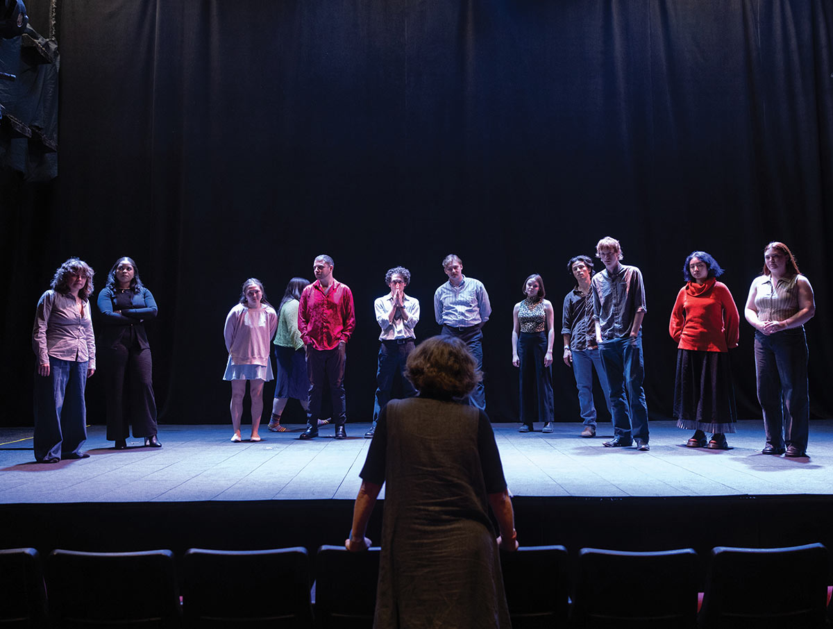 A director from behind watching a line of actors standing on stage.