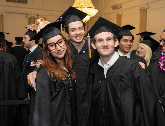Three Emerson College students pose together in caps and gowns at the School of Film undergraduate diploma ceremony.