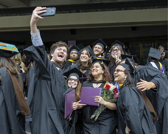 Graduates pose for a group selfie after the School of Arts graduate hooding ceremony.