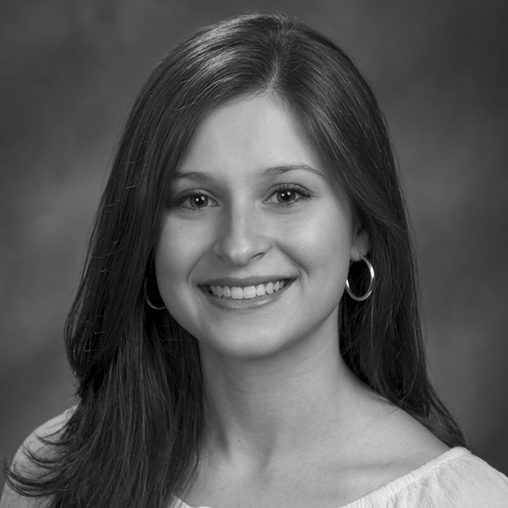 Black-and-white studio portrait of a smiling Sonia Rincón with long dark hair wearing hoop earrings.