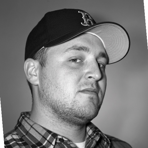 Black-and-white close-up of Trevor Gooby wearing a baseball cap and plaid shirt.