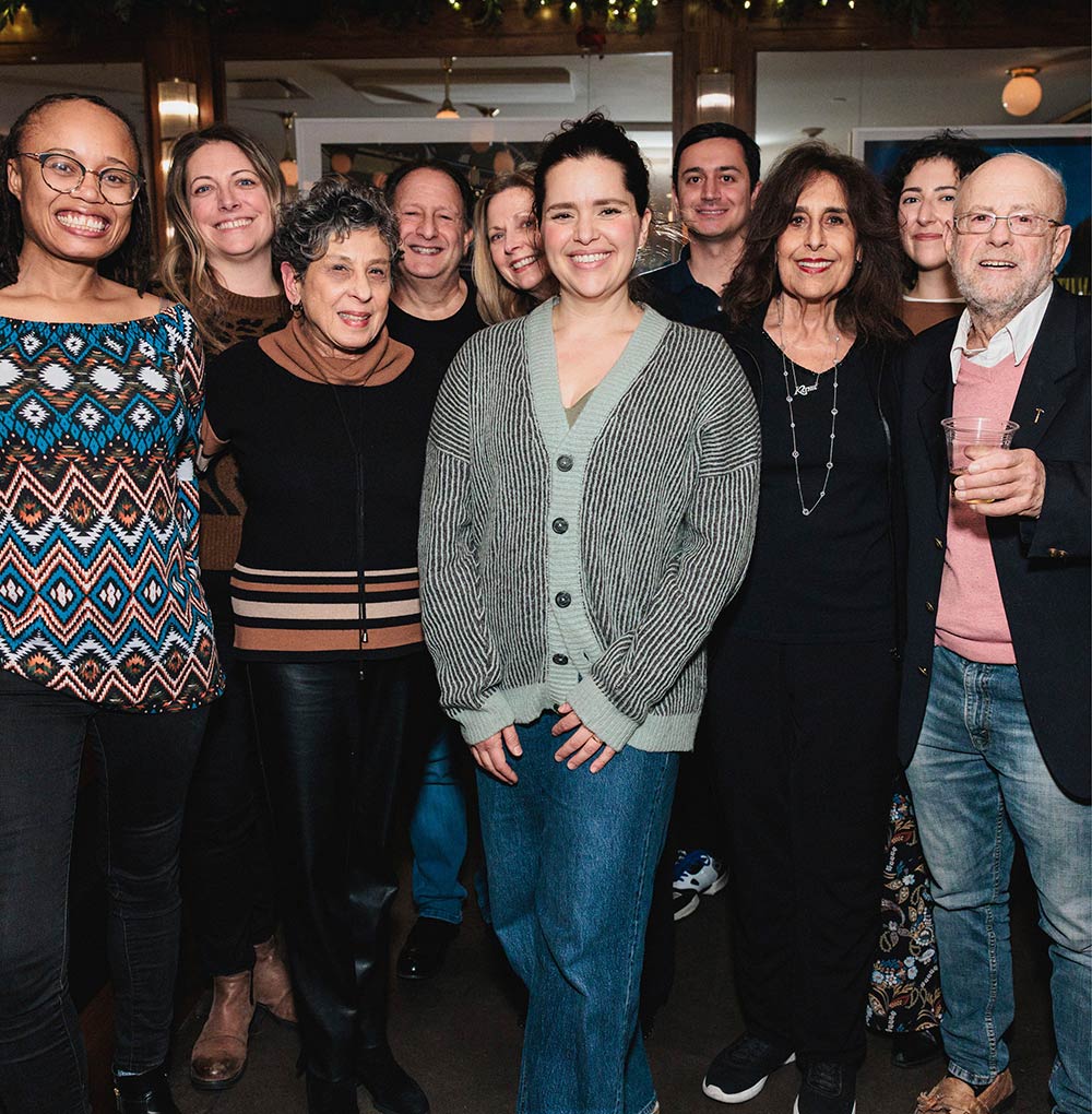 A group of people smiles together while posing for a picture indoors.