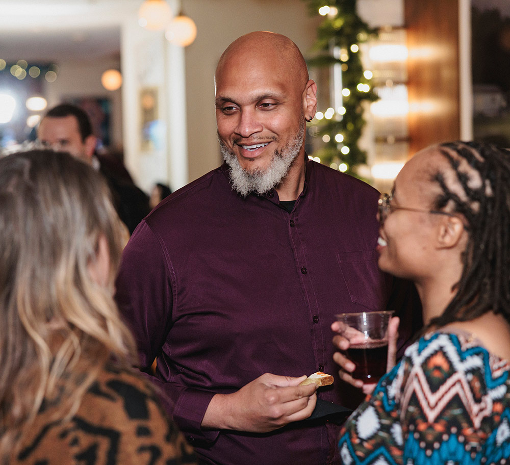 Maxine Stewart ’02 and her guest, Tim Foxx, chats with two women at an event gathering.