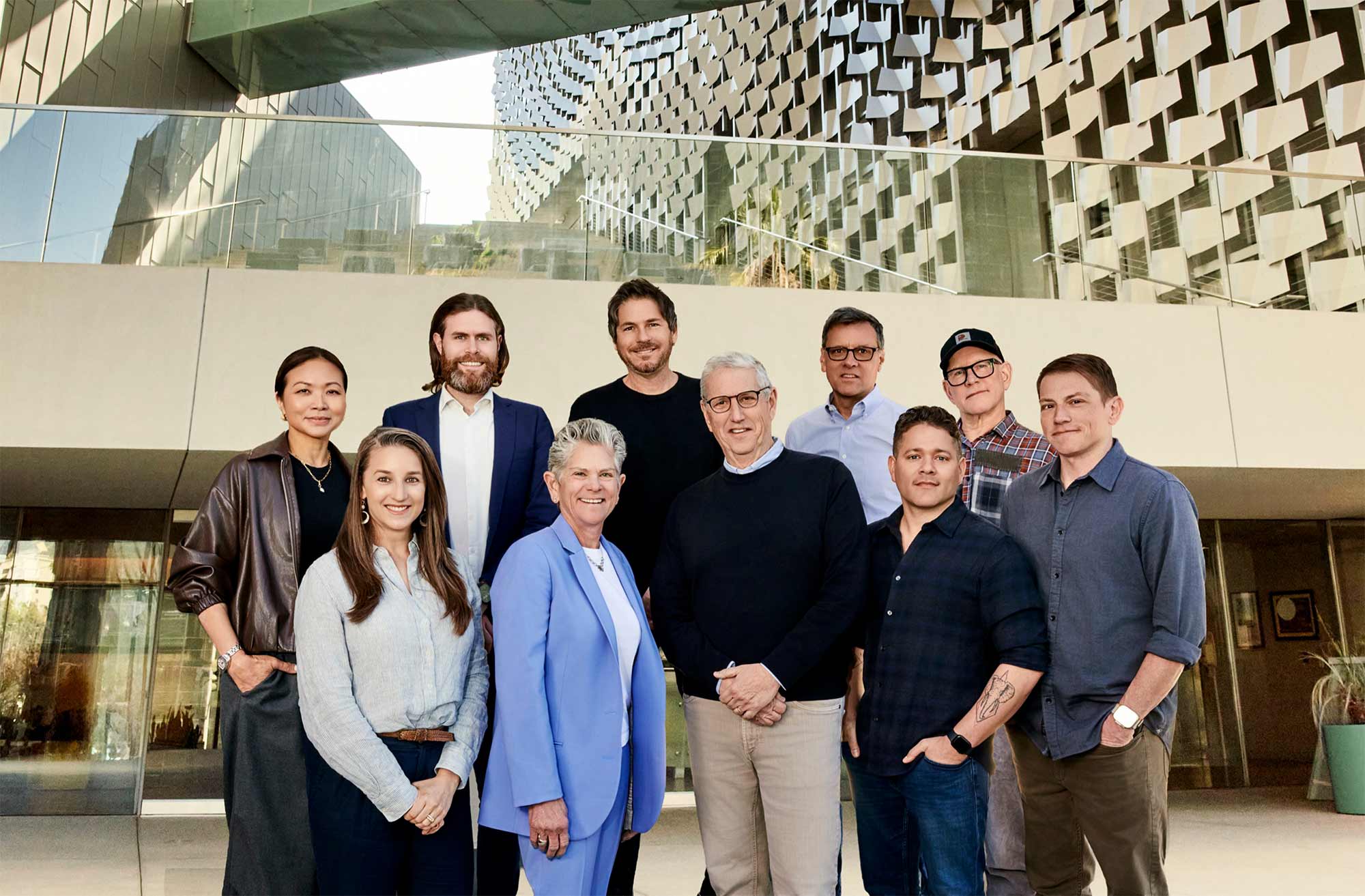 Board members and Chair Doug Herzog pose outside modern architecture on steps.